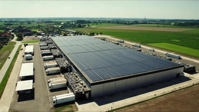 Luftbild eines Logistikzentrums mit Solardach und Lkw an den Laderampen